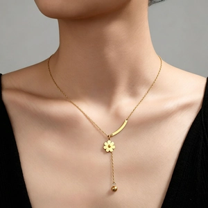 Détail du collier marguerite en titane doré avec pendentif fleur et chaîne à pampilles