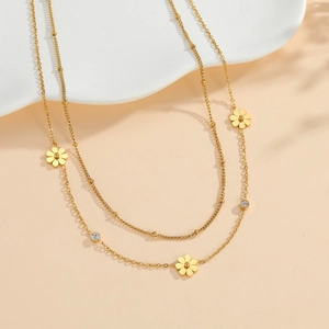 Élégant collier double épaisseur doré à fleurs marguerites et cristaux sur fond doux