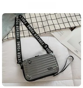 Silver hard shell crossbody bag with suitcase ridges and Forever Young strap detail