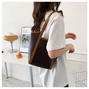 Side view of large deep brown PU leather tote bag worn on shoulder by a model