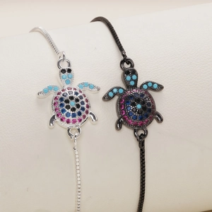 Detail of silver and black turtle bracelets with multi-colored zircon stones on ivory leather