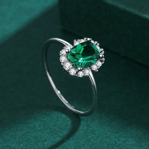 Macro view of emerald-cut green gemstone ring with halo stones on silver band