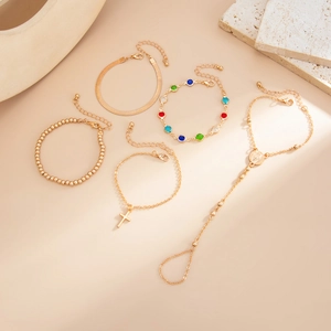 Detailansicht eines 5-teiligen Gold-Armbandsets mit Kreuzanhänger und Perlen