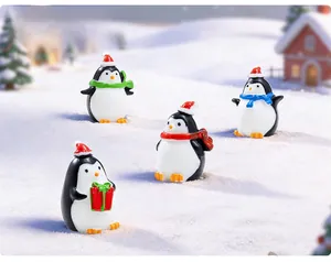 Macro shot of miniature Christmas penguins with red hats and colorful scarves in snow