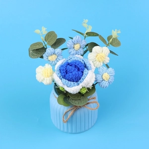 Composizione di rose all'uncinetto bianche e blu in un vaso di ceramica celeste decorativo