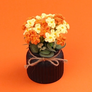 Handmade knitted orange and beige flowers in a black textured pot for home decor
