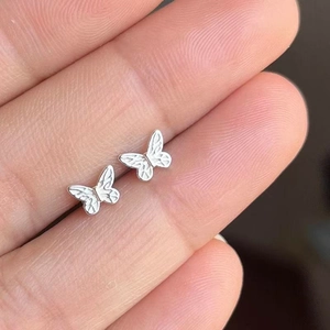 Micro 925 sterling silver butterfly stud earrings shown on finger for scale reference