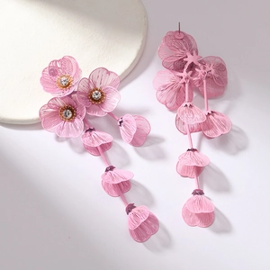 Close-up of pink hollow woven flower tassel earrings with sparkling rhinestone centers