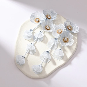 Close-up of matte white floral earrings with metal mesh petals and long tassel details