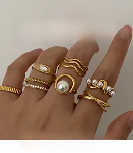 Close-up of stacked gold-plated ring set with pearls and zircons on a hand