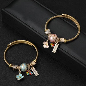 Detail of twisted gold bangle bracelets with enamel flower charms and handmade charms