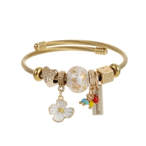 Detail of golden wire bracelet with enamel flower charm and handmade heart beads