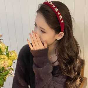 Detail of burgundy velvet headband featuring white pearls and golden flower embellishments