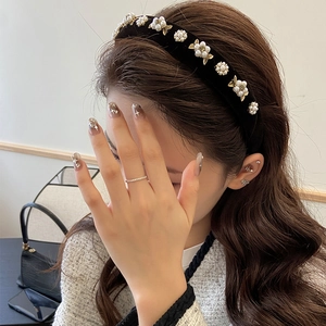 Detail of black velvet headband featuring pearl flowers and golden leaves on model