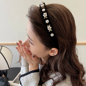 Close-up of velvet flower headband with white pearls and gold metal leaves on a model