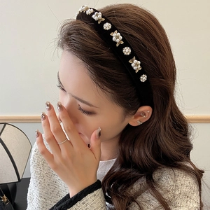 Elegant black velvet headband featuring pearl flowers and golden leaves on a model