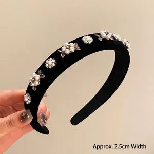 Detail view of a 2.5cm wide black velvet headband with pearls and metallic leaves