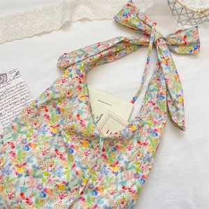 Detail of floral tote bag featuring a large bow shoulder strap and colorful summer patterns