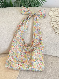 Floral canvas shoulder bag with large bow strap detail on light textured background