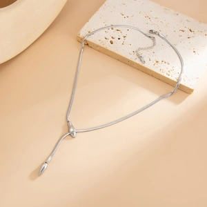 Macro shot of silver Y-shaped snake bone chain necklace with sleek pendant on stone base