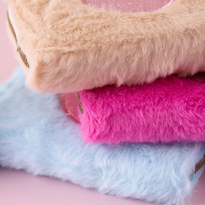 Macro shot of fluffy plush coin purses in khaki, pink and blue with gold zippers