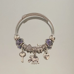 Close-up of elephant and heart charms on a silver beaded charm bracelet with purple beads