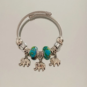 Detail view of silver twisted cable bracelet with turquoise beads and elephant charms