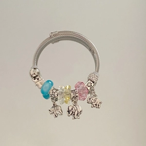 Macro detail of elephant charms and multifaceted colorful beads on a woven steel bracelet