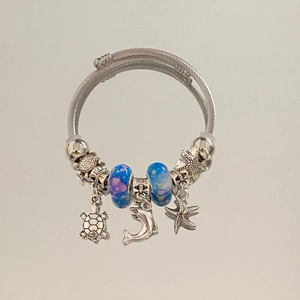 Detail of silver cable bracelet with sea turtle dolphin charms and blue glass beads