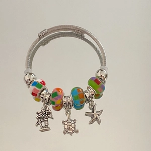 Detailed view of ocean-themed charms featuring turtle, starfish and palm tree on a bracelet