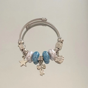 Macro shot of silver cable bracelet with heart 'love you' charm and blue beads