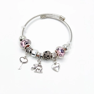 Detail van de zilveren kralenarmband met roze glaskralen en een hart sleutel olifant