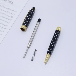 Deconstructed black polka dot ballpoint pen with gold clip and metallic refill
