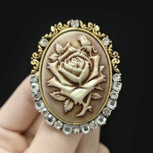 Macro shot of vintage gold brooch featuring delicate rose relief and crystal accents