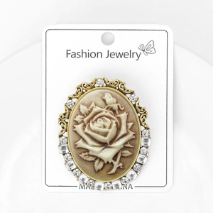 Vintage palace style oval brooch featuring embossed rose and bird with crystal border