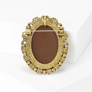 Back view of vintage oval brooch with antique gold metal frame and secure pin closure