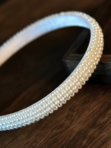 Gros plan sur un serre-tête élégant orné de quatre rangées de perles blanches