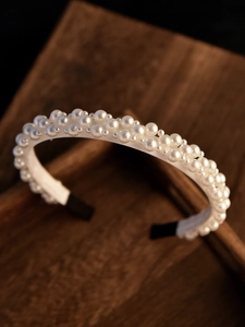 Gros plan d'un serre-tête en perles avec des perles blanches étagées sur un fond en bois sombre