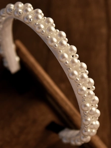 Gros plan détaillé d'un serre-tête en soie blanche orné de perles irrégulières pour mariée