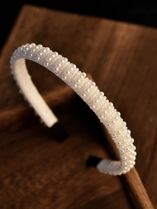 Détail de perles blanches élégantes minutieusement cousues sur un serre-tête de mariée