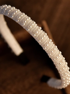 Gros plan détaillé de perles blanches sur un serre-tête de mariée avec tissu protecteur