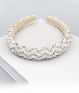 Detailed close-up of wide headband with pearls and rhinestones on a display stand