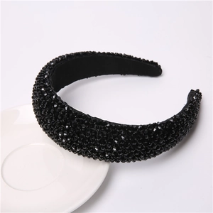 Close-up of black beaded wide headband placed on a white ceramic dish for detail