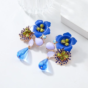 Detail of floral earrings featuring blue resin petals, yellow rhinestones and drop pendants