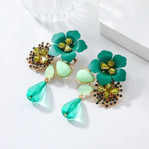 Detailed macro view of resin flower earrings with green stones and sparkling rhinestones