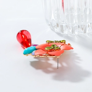 Macro detail of colorful resin flower earrings with beaded crystals and gold-tone metal studs