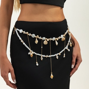 Detail of bohemian gold waist chain with pearls and assorted seashells on a model