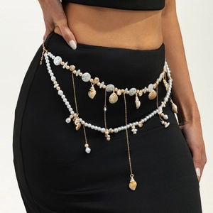 Detail of gold layered body chain with pearls and shells on a black dress