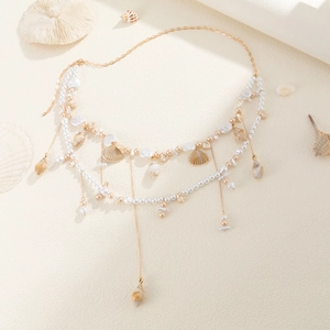 Detail of layered gold waist chain with white pearls and assorted sea shell pendants