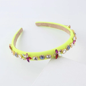 Neon yellow headband with colorful rhinestones and velvet lining on a geometric stand